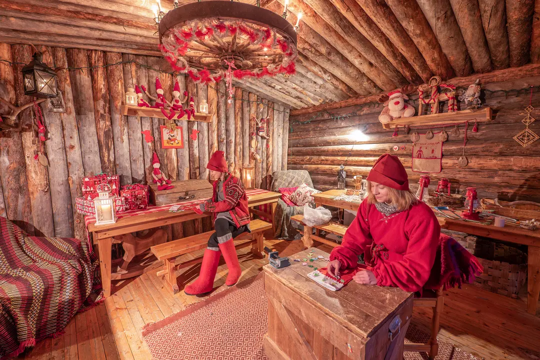 Cosy log cabin decorated for Christmas with elves surrounded by gifts and festive decorations