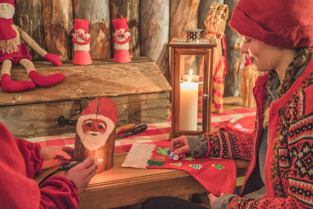 Elves making Christmas crafts by candlelight in a rustic log cabin workshop