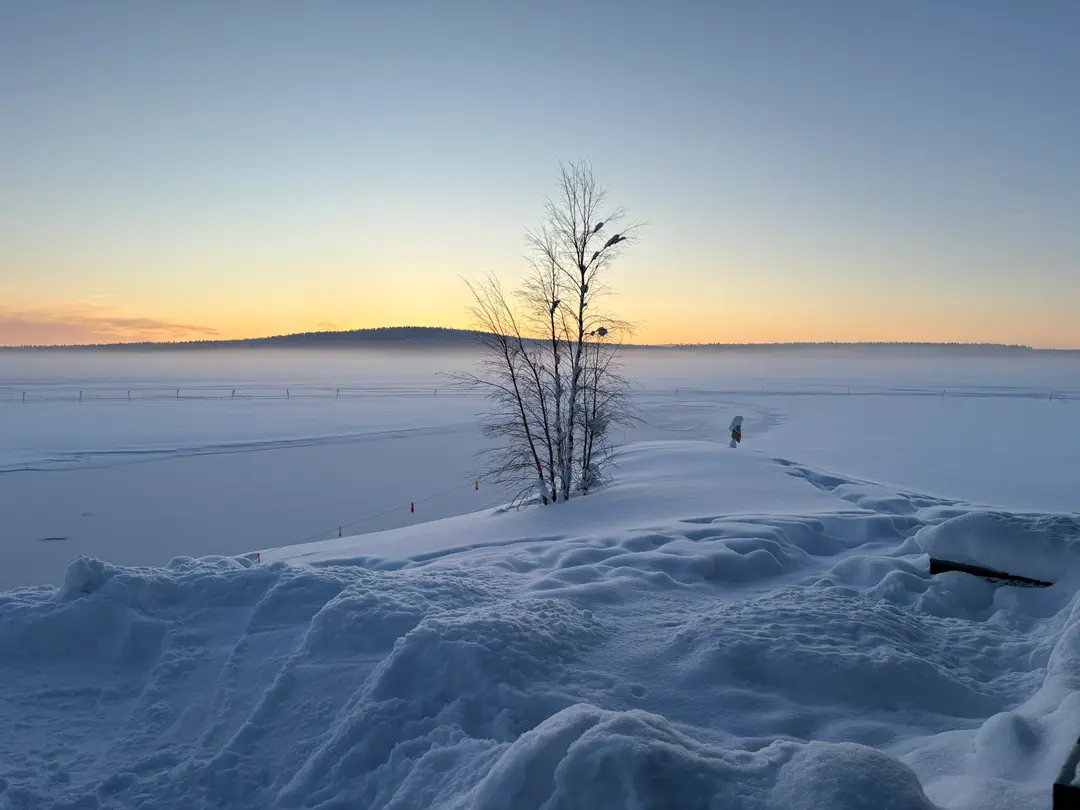 Serene winter sunset across a vast frozen lake with distant forested hills