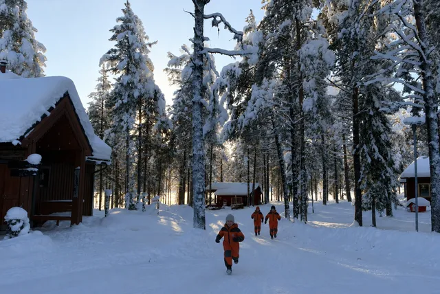 Family walking through the snow at a Lapland resort after arriving